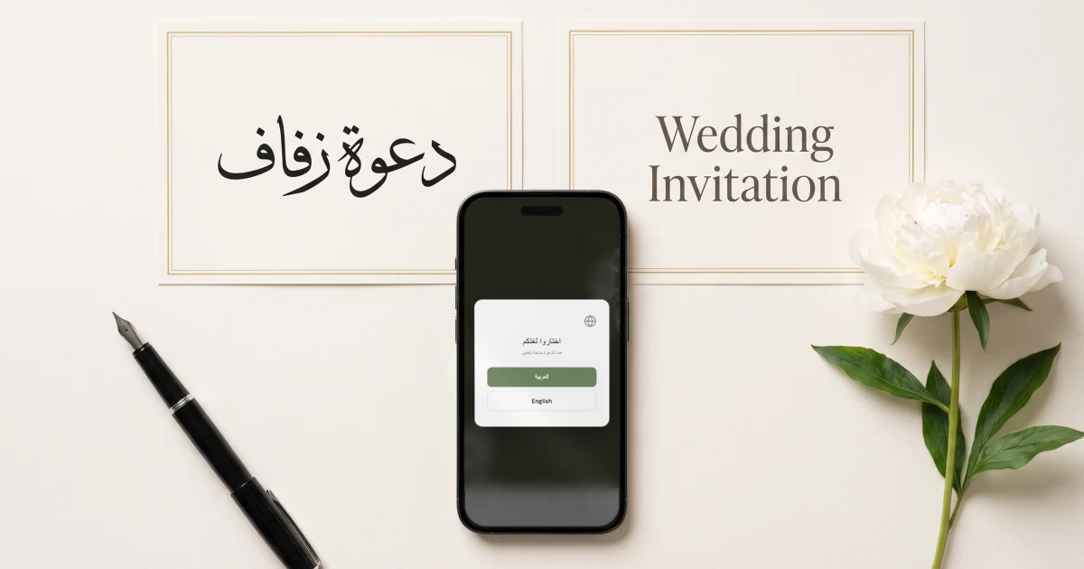 دعوة زفاف بالعربي والإنجليزي برابط واحد: جوال يعرض نافذة اختيار اللغة بين العربية والإنجليزية، فوقه كرتان بالتصميم نفسه، دعوة زفاف بالخط العربي وWedding Invitation بالإنجليزية، مع قلم حبر ووردة فاوانيا بيضاء
