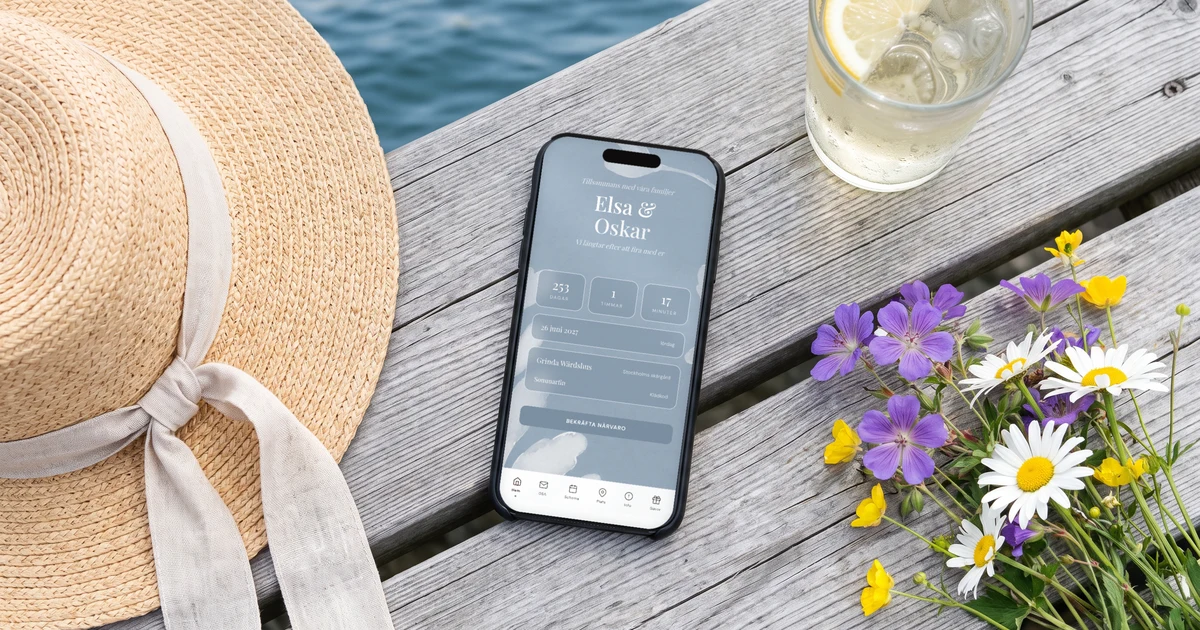 Exempel på bröllopshemsida i mobilen: omslaget med parets namn, datum och nedräkning, liggande på en brygga i skärgården bredvid en sommarhatt och ett glas fläderdricka