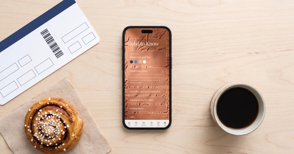 Bröllopsinbjudan för utländska gäster: mobilen visar informationssidan på engelska med förklaring av klädkoden kavaj och svenska bröllopstraditioner, bredvid ett boardingkort och en kanelbulle