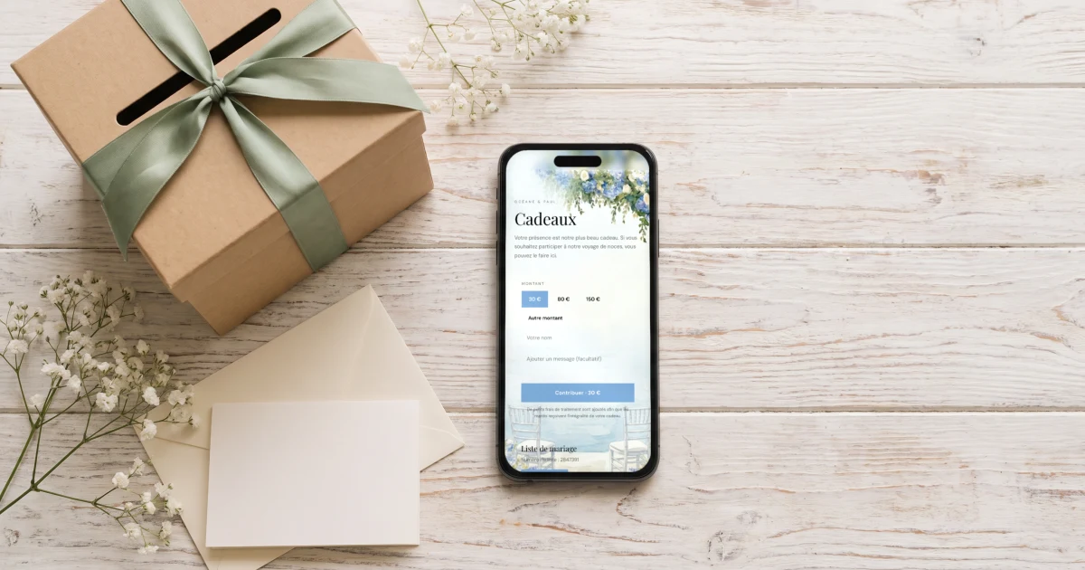 Cagnotte de mariage en ligne : un téléphone affiche la cagnotte sur le faire-part à côté d'une urne de mariage et d'enveloppes