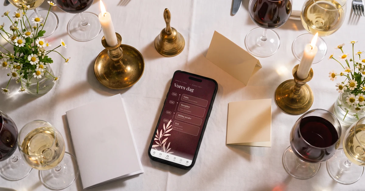 Toastmaster til bryllup: en telefon ligger fladt ved siden af et foldet kort, et sanghæfte og en lille klokke på en dækket festbord med levende lys, telefonen viser bryllupsprogrammet med klokkeslæt