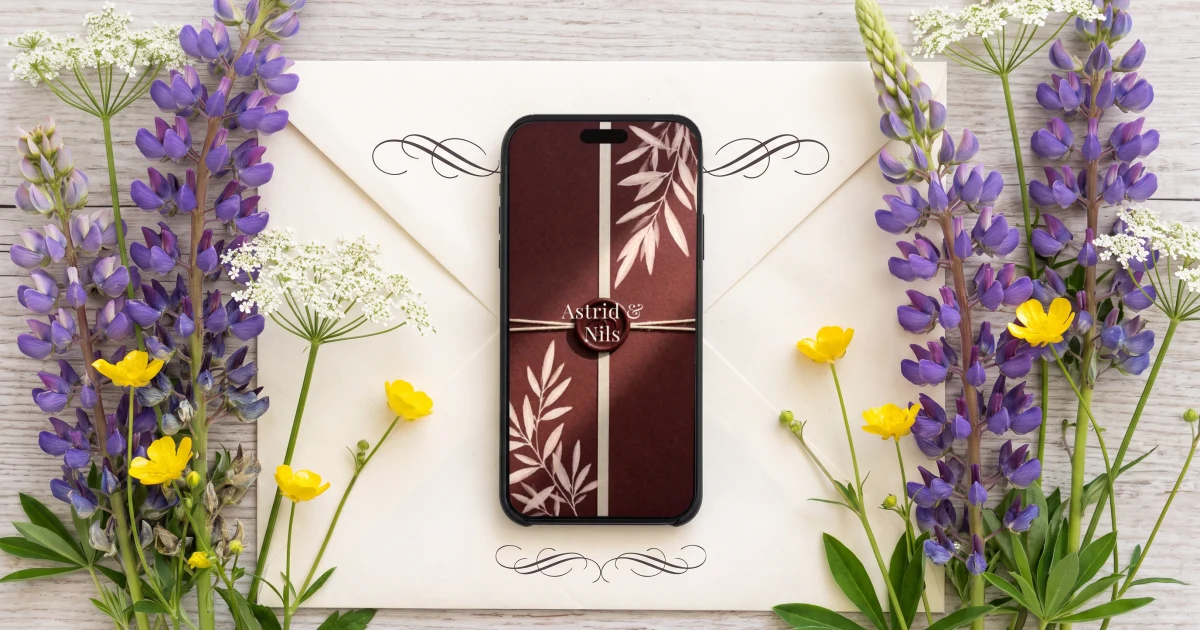 Digital bröllopsinbjudan med OSA: mobilen visar öppningen med ett vaxsigill och parets namn, liggande på ett kuvert med kalligrafiska ornament bland midsommarblommor