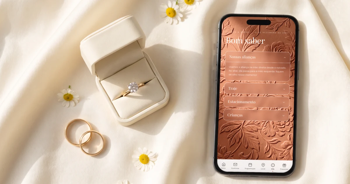 Em qual mão se usa a aliança: alianças douradas e uma caixinha com solitário sobre seda creme, ao lado de um celular deitado mostrando a seção Nossas alianças do convite, que explica a troca da mão direita para a esquerda no casamento