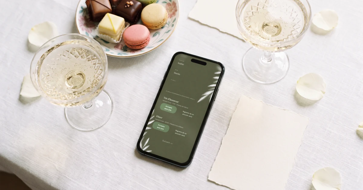 Faire-part vin d'honneur et repas : un téléphone affiche la réponse au vin d'honneur et au repas à côté de coupes et de deux cartons