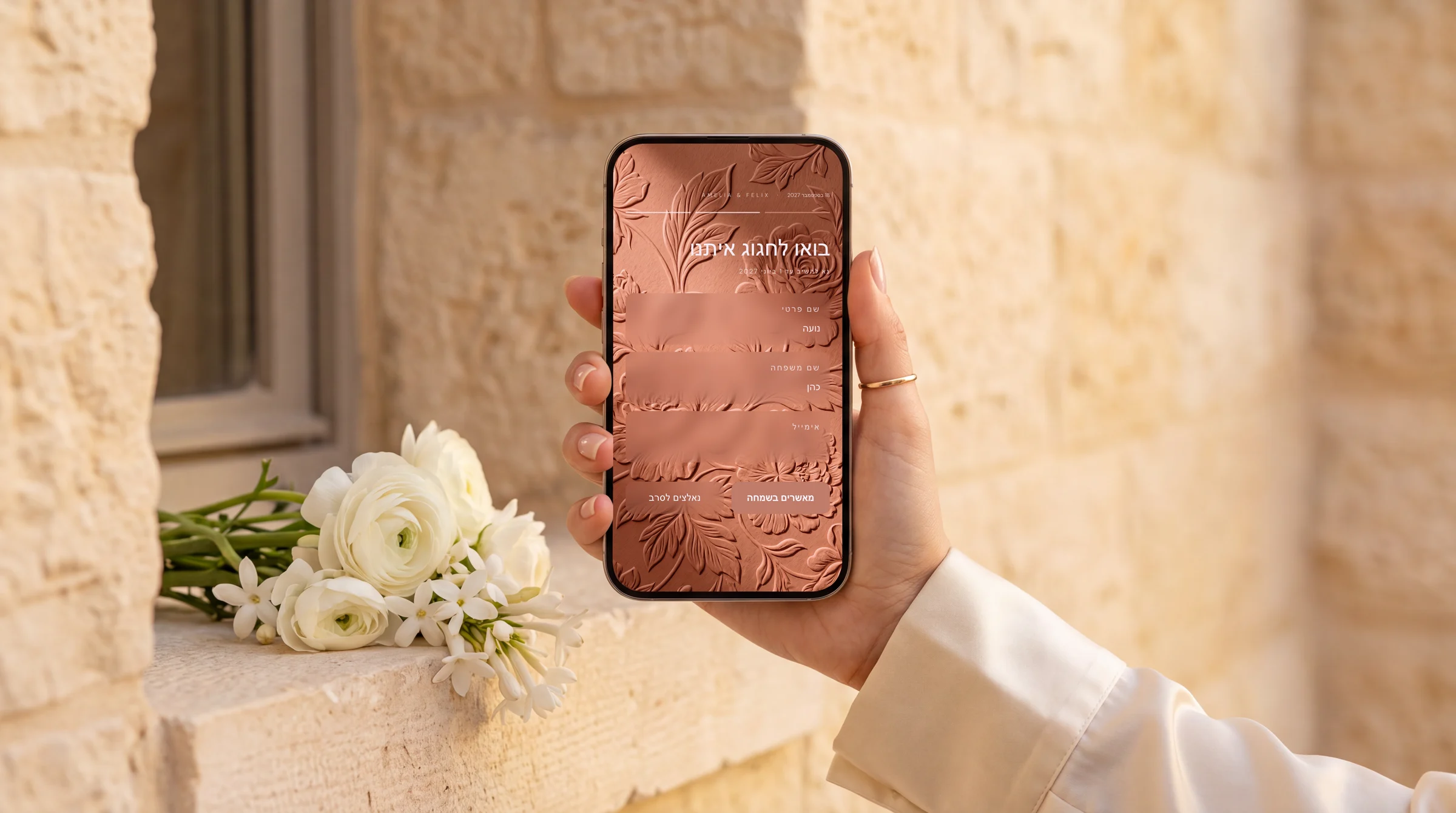 הזמנה דיגיטלית לחתונה עם אישורי הגעה: יד מחזיקה טלפון עם טופס אישור הגעה בעברית מול קיר אבן ירושלמית מואר בשמש אחר הצהריים, עם זר פרחים לבנים על אדן החלון