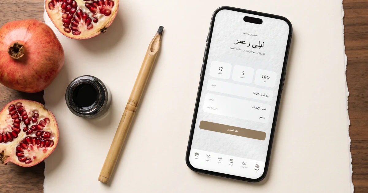 Hebrew and Arabic wedding invitation: a phone shows a right to left Arabic wedding invitation beside a reed pen, an inkwell and pomegranates