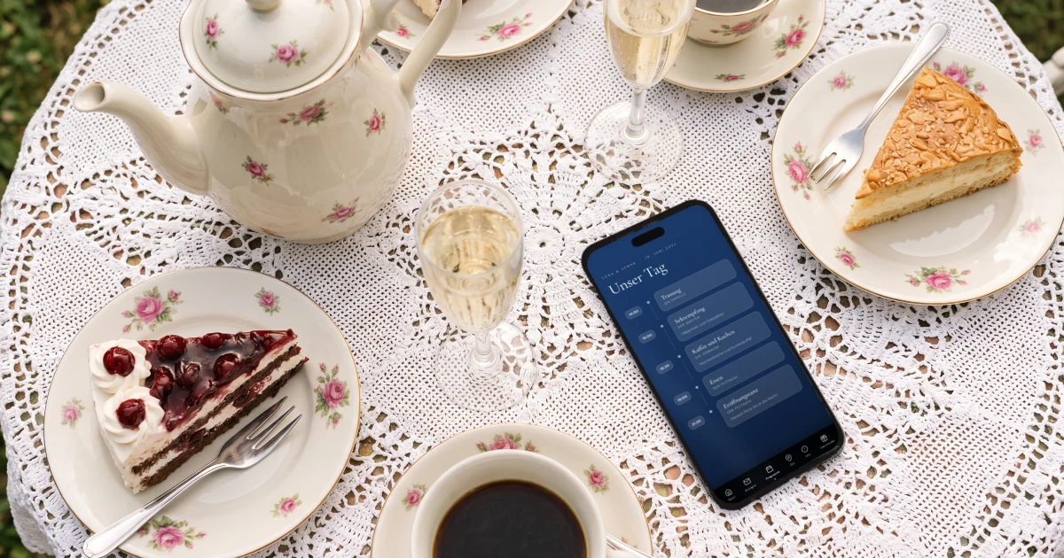 Hochzeit Tagesablauf: ein Handy zeigt den Ablauf mit Sektempfang und Kaffee und Kuchen neben Kuchen und Sektgläsern