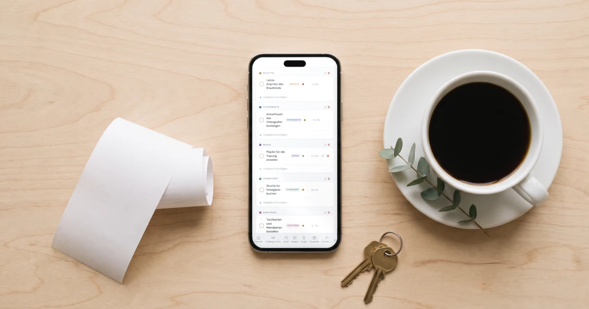 Hochzeitsplaner-App ohne Abo: ein Handy zeigt die Hochzeits-Checkliste neben einem Kassenbon und Schlüsseln