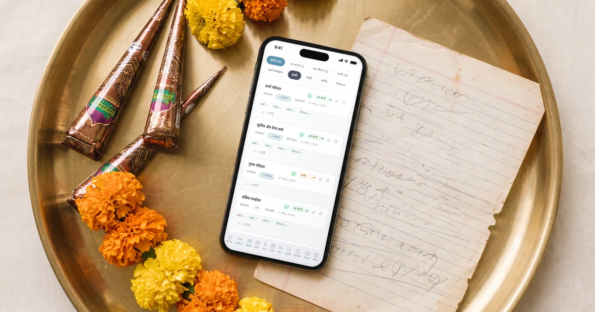पीतल की थाली में मेहंदी के कोन, गेंदे की माला और हाथ से लिखी मेहमानों की पुरानी सूची के पास मेज़ पर रखा फ़ोन, जिसमें शादी की गेस्ट लिस्ट ऐप में हल्दी, मेहंदी, संगीत और रिसेप्शन के अलग-अलग RSVP दिख रहे हैं