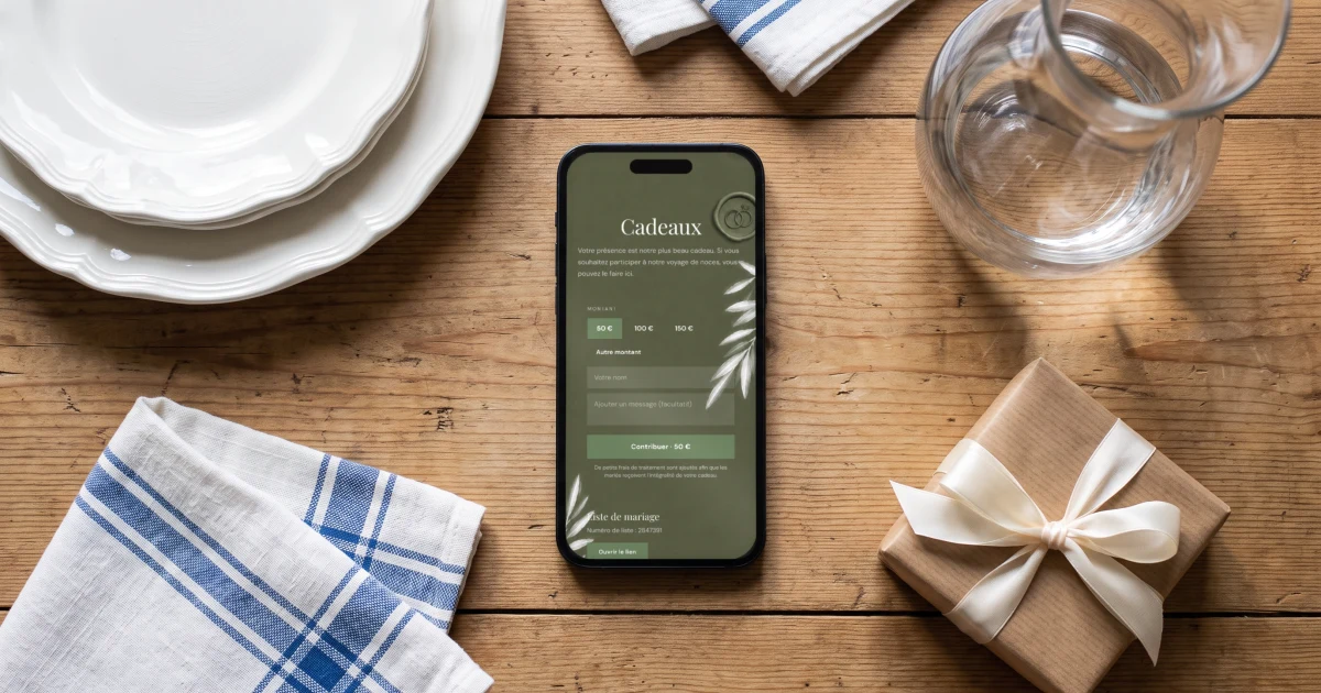 Liste de mariage : un téléphone affiche la page Cadeaux du faire-part en français, à côté d'assiettes en faïence, de torchons en lin et d'un paquet cadeau