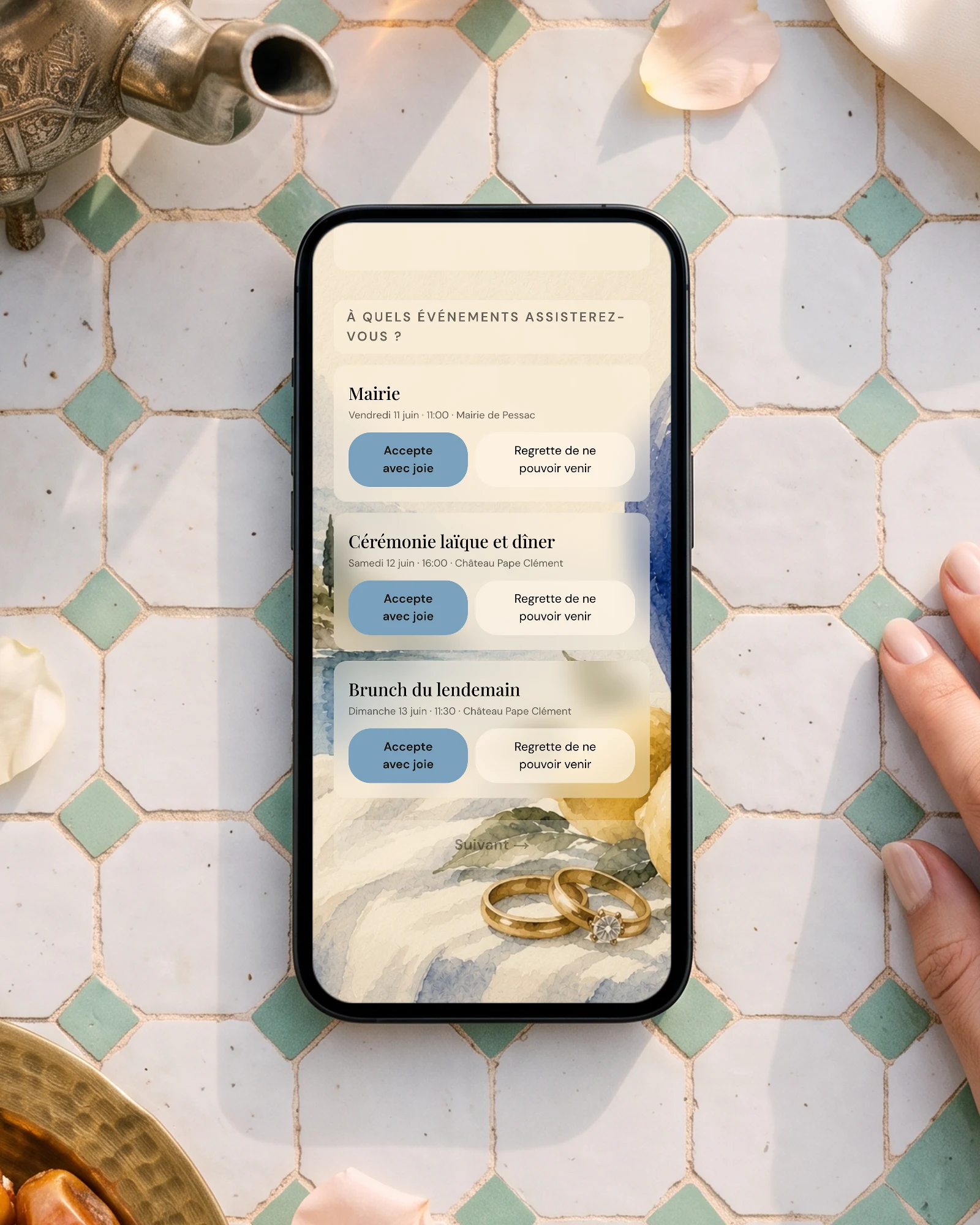 Mariage à l'étranger au Maroc, RSVP par événement : un téléphone posé sur une table de zellige, entre une théière en argent, des verres de thé à la menthe et des dattes, affiche la question À quels événements assisterez-vous avec Mairie, Cérémonie laïque et dîner, et Brunch du lendemain
