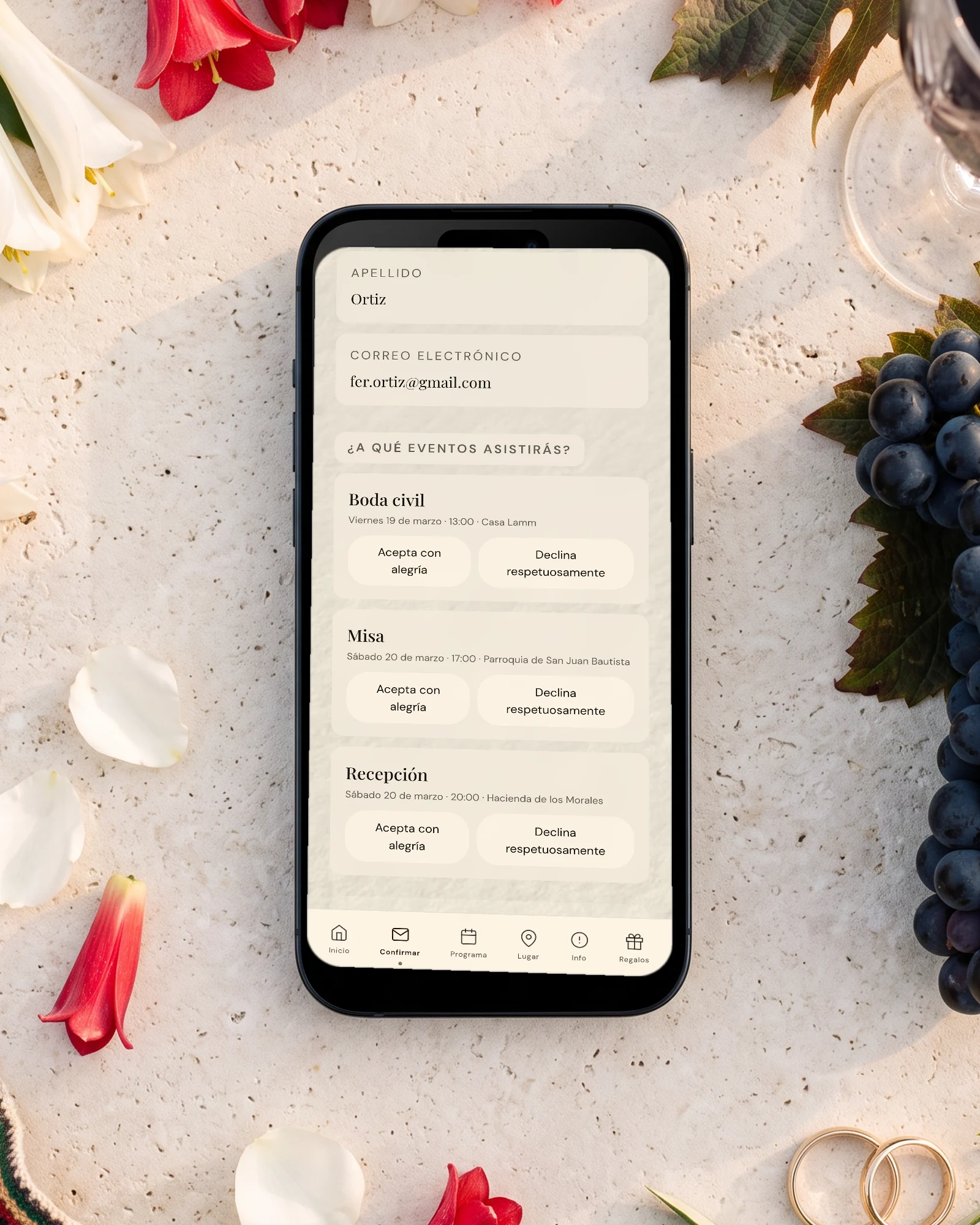 Confirmación de asistencia por evento: el teléfono muestra la boda civil, la misa y la recepción, cada una con su respuesta, entre copihues, uvas, una copa de vino y un chamanto