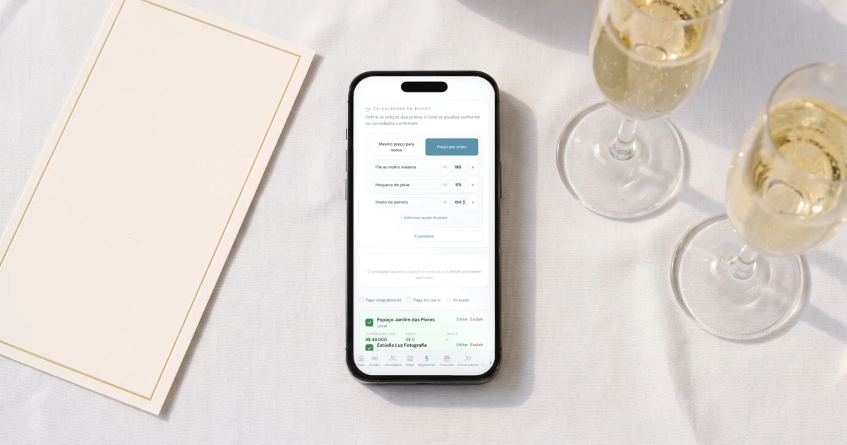 Orçamento de casamento para 100 convidados: celular deitado sobre uma toalha branca mostrando a calculadora do buffet com o preço de cada prato, ao lado de um cardápio impresso do jantar e duas taças de espumante