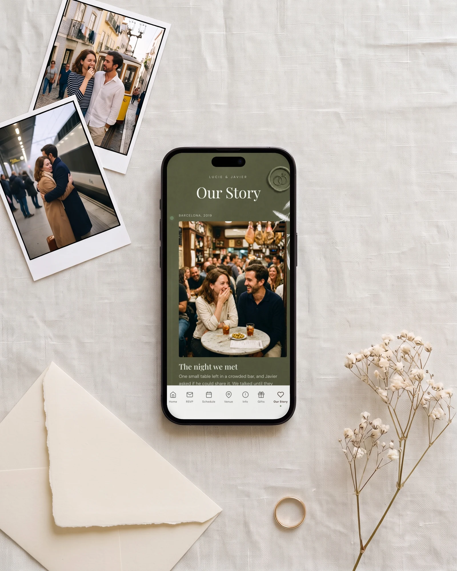 Our Story wedding website example: a phone shows the Our Story page of Lucie and Javier, with a photo of the night they met, next to two printed photos of the couple, a cream envelope and a gold ring