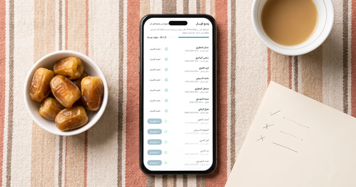 إرسال دعوة الزواج على الواتساب: جوال يعرض وضع الإرسال بشريط التقدم والضيوف الذين أُرسل لهم، بجانب تمر سكري وفنجان قهوة وورقة بعلامات على وسادة سدو