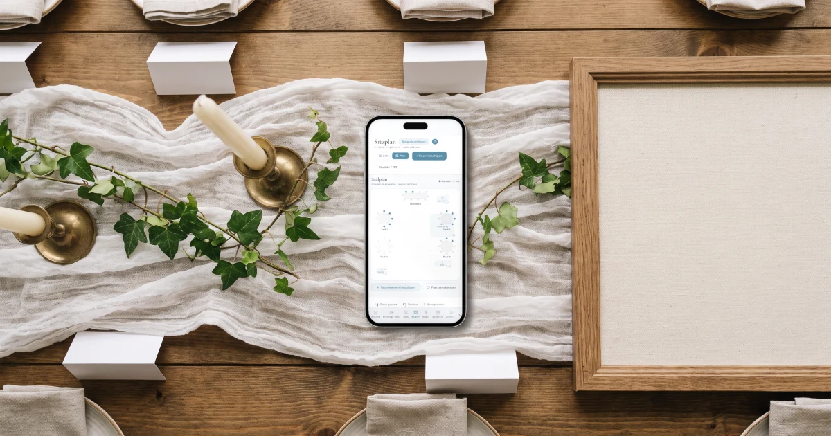 Sitzplan für die Hochzeit erstellen: ein Handy zeigt den Tischplan neben Tischkarten