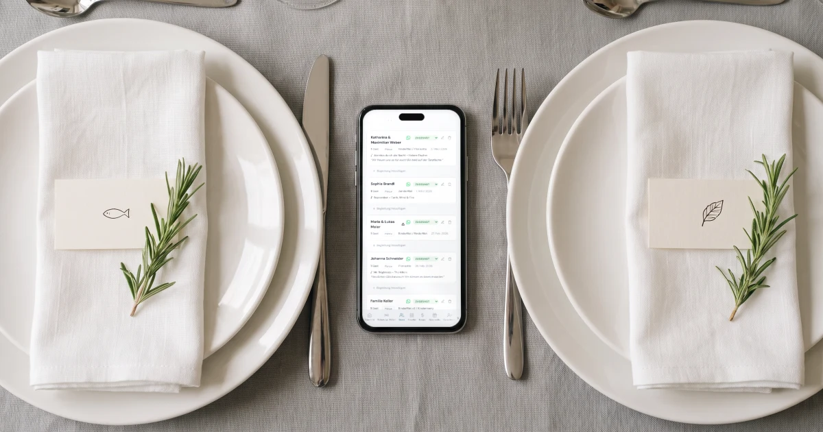 Tischkarten mit Menüwahl: Tischkarten mit Symbolen für Fisch und vegetarisch auf Tellern neben einem Handy mit der Gästeliste und der Menüwahl