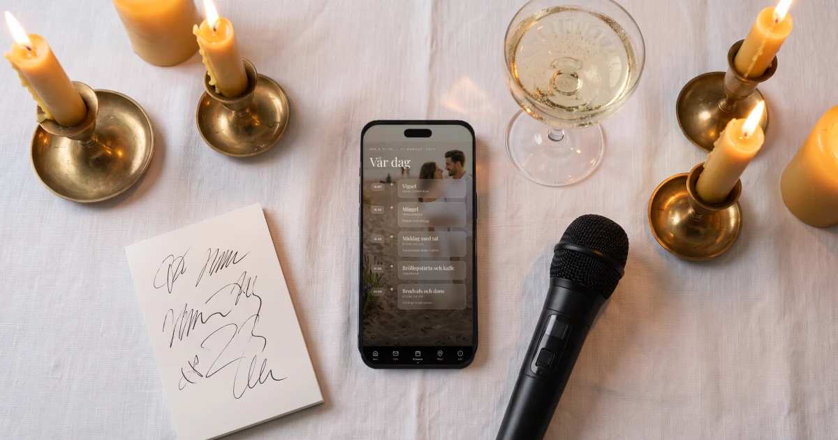 Toastmaster på bröllop: en handskriven talarlista, en mikrofon och ett glas bubbel på ett dukat bord, bredvid en mobil som visar kvällens program
