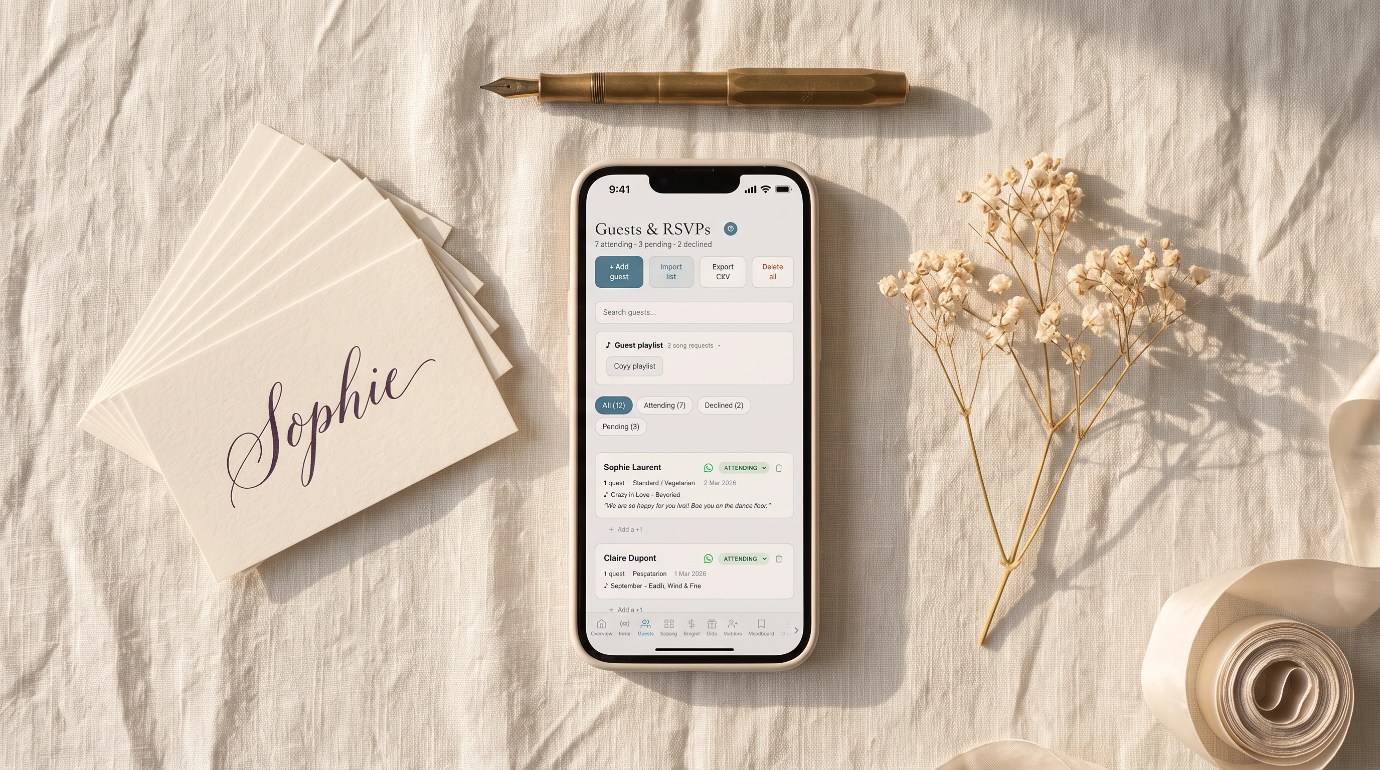 Wedding guest list and RSVP tracker app on a phone lying flat on ivory linen with calligraphy place cards and a fountain pen